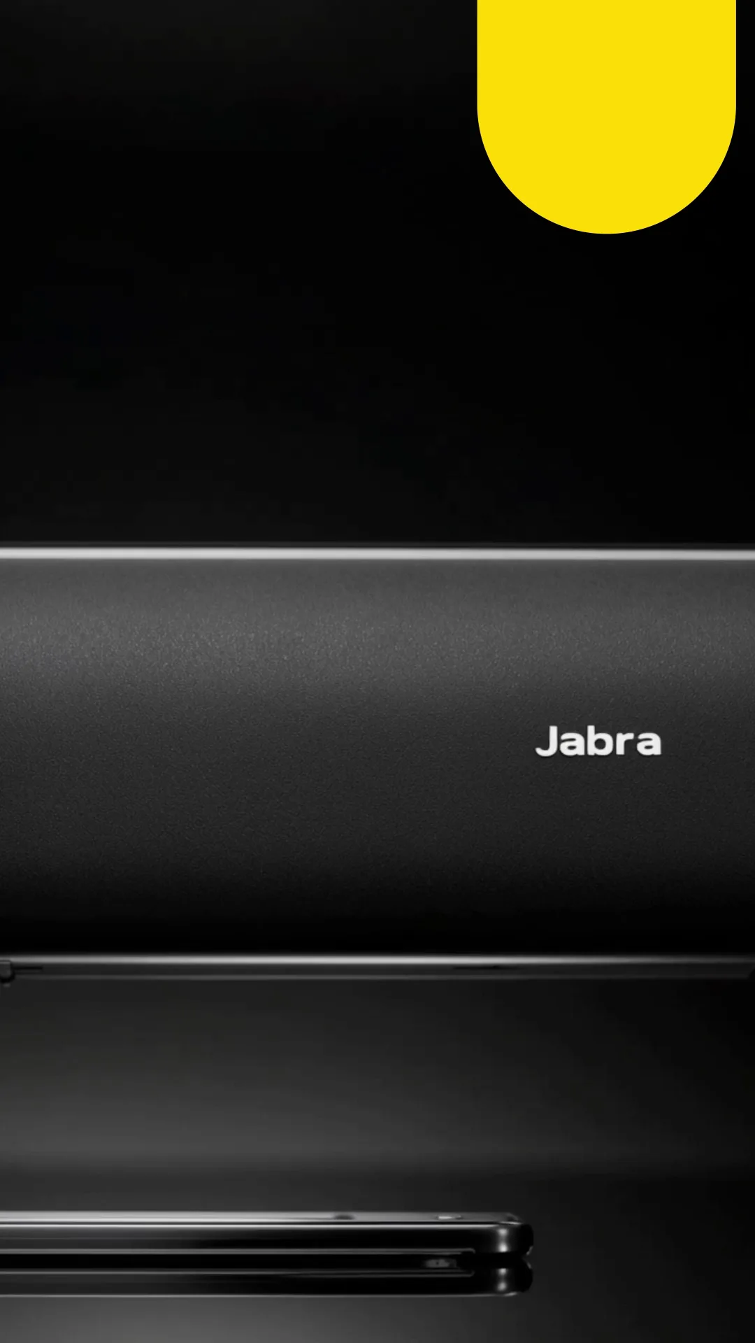 Close-up of a black Jabra speaker with its white logo, against black with a yellow arch at top right