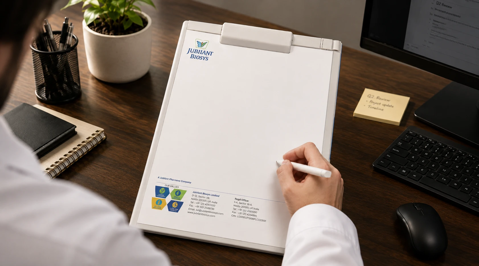 Jubilant Biosys letterhead and stationery design on a clipboard